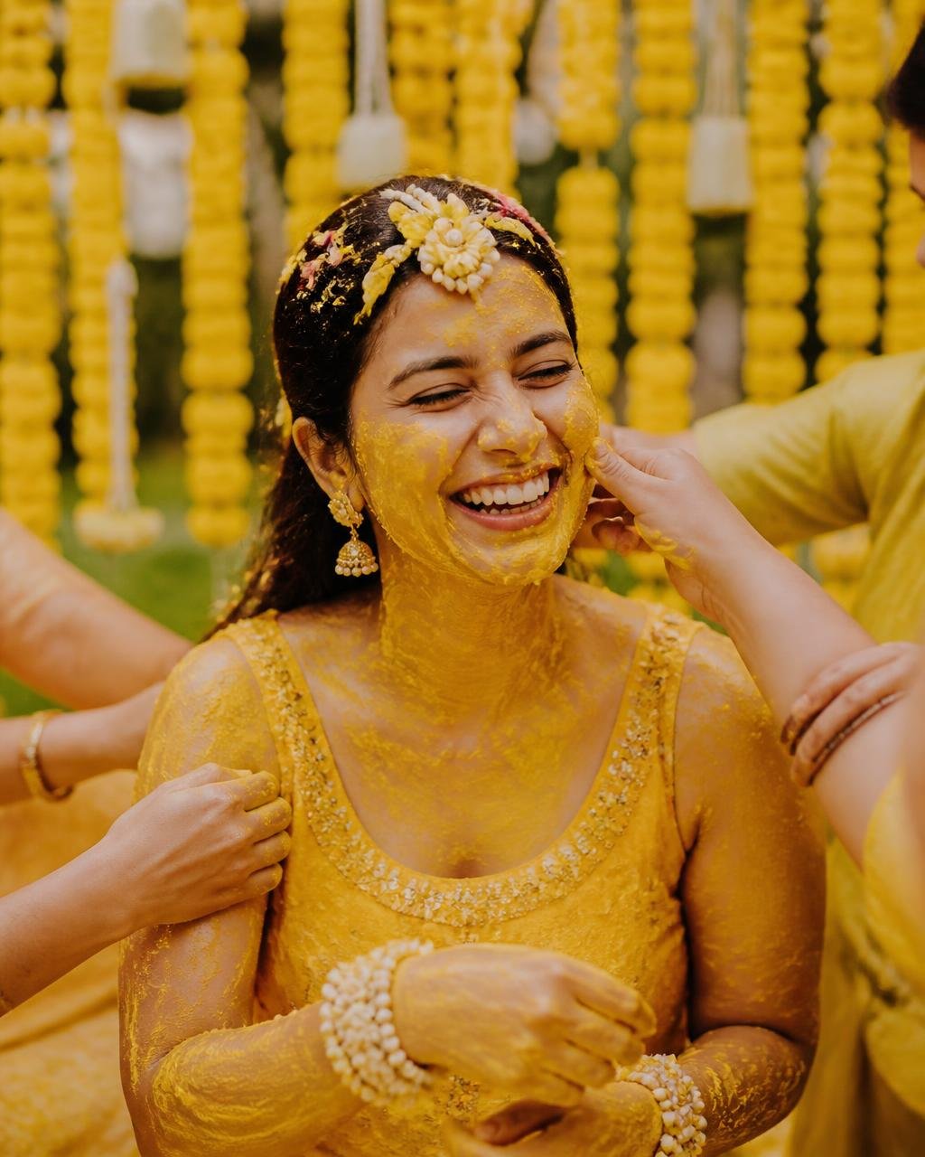 Family applying haldi to the bride surrounded by marigolds