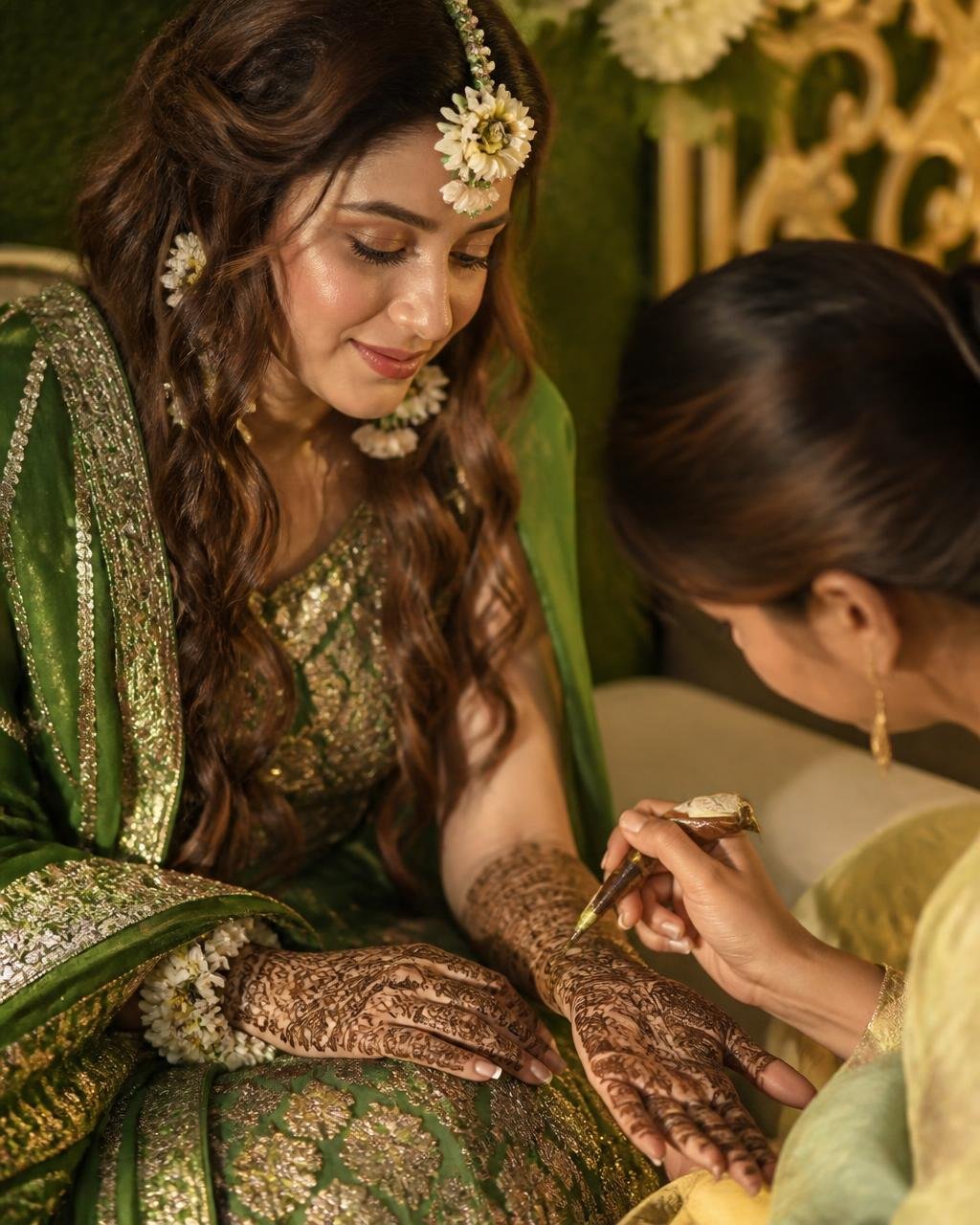 Detailed henna being applied to the bride's hands during the mehendi ceremony