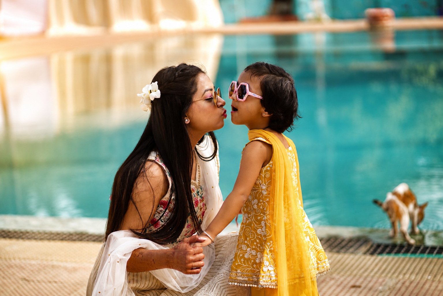 Tender candid of the bride and a little guest sharing a kiss by the water