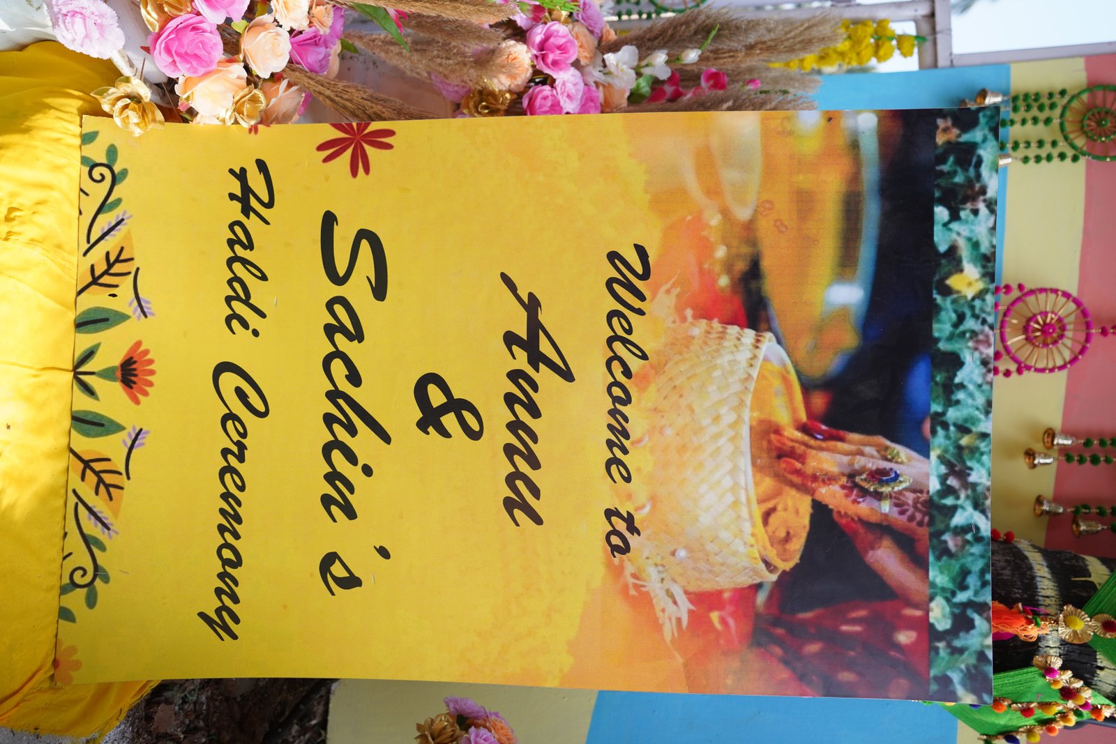 Hand-painted welcome signage and floral decor set up for the haldi ceremony
