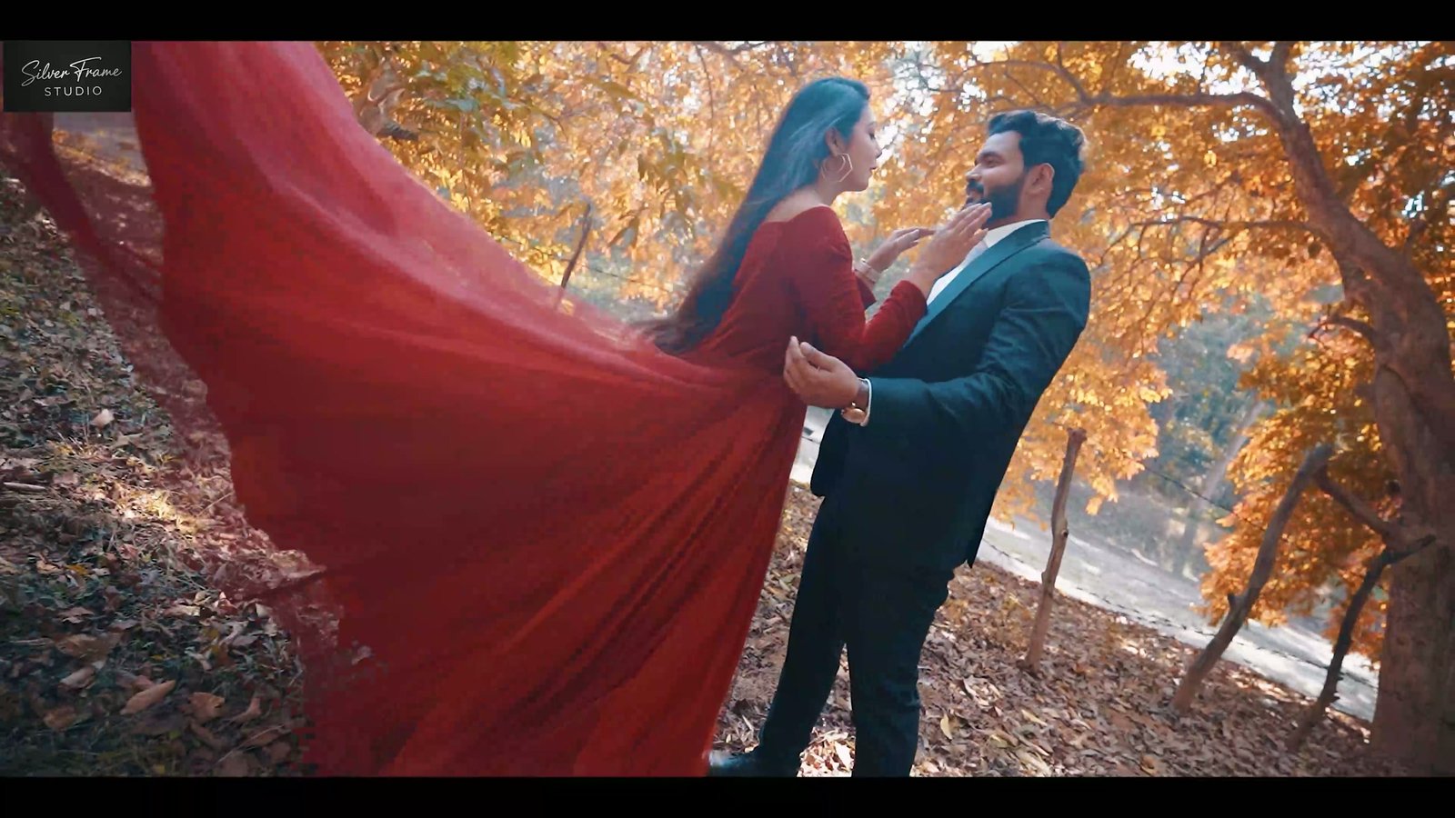 Ashutosh and Sannidha in a flowing red gown among autumn trees