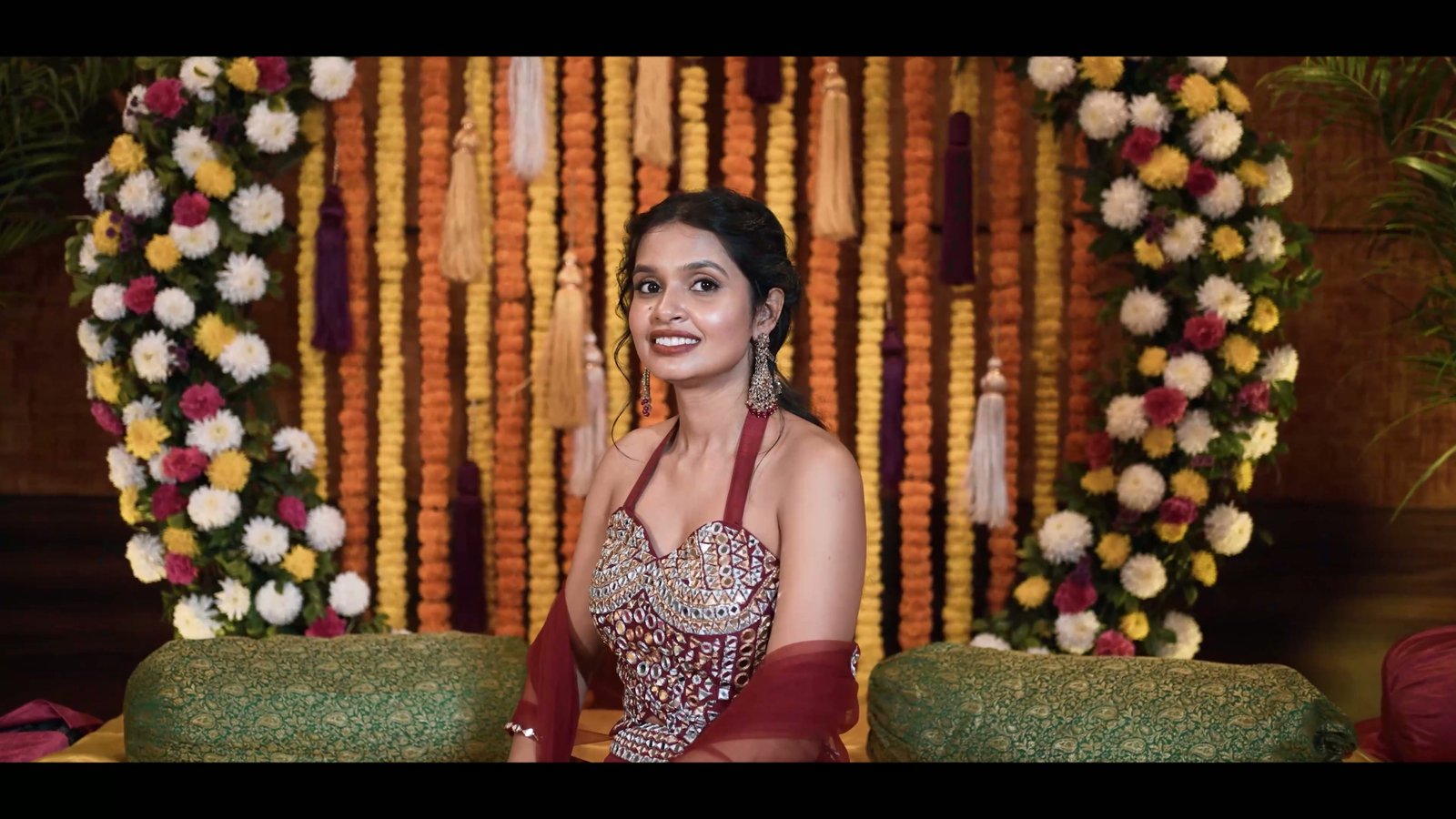 Bride seated on a marigold-draped stage during her mehendi celebration