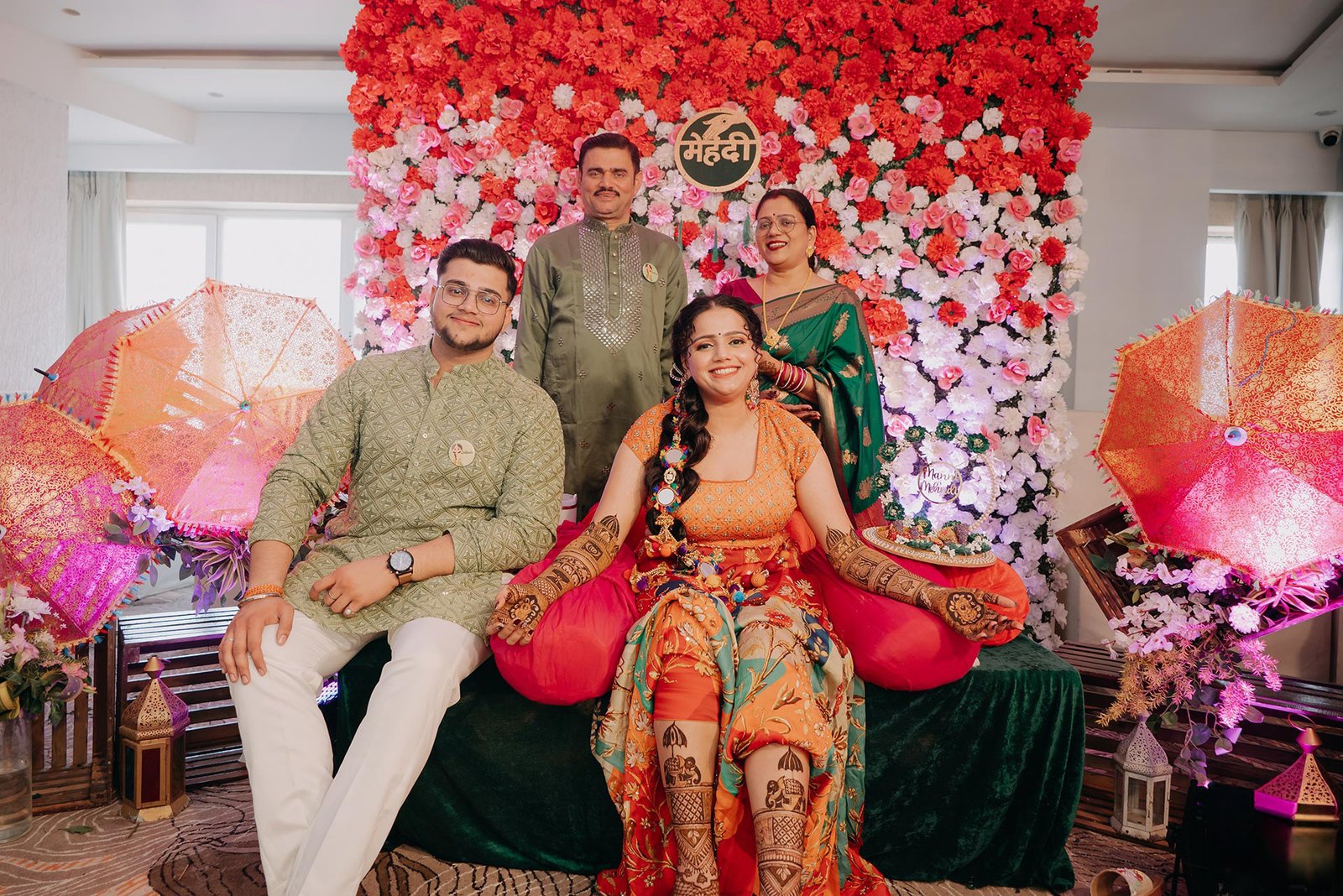 Bride with her family on the mehendi stage surrounded by florals
