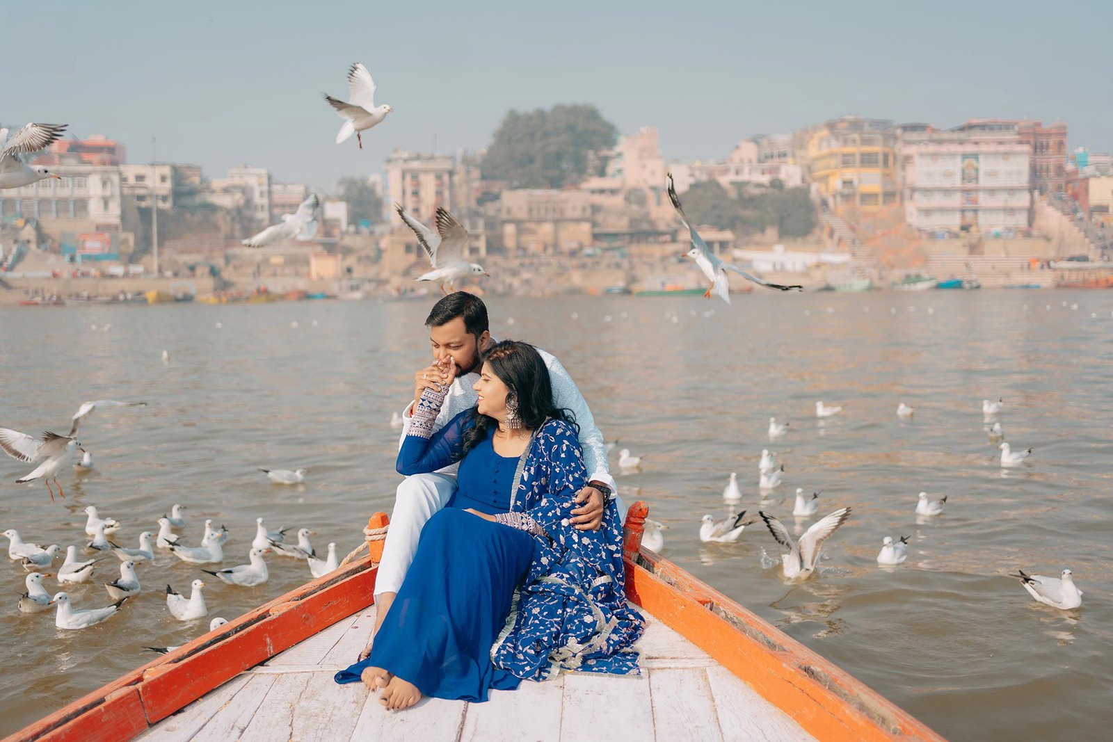 Couple on a wooden boat surrounded by birds during a pre-wedding shoot