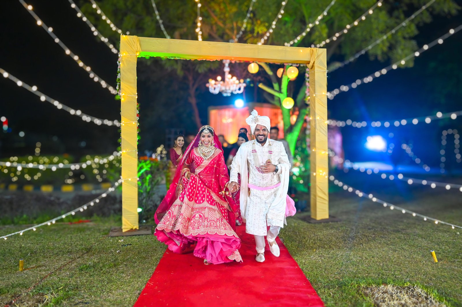 Bride and groom walking in together under strings of festoon lights